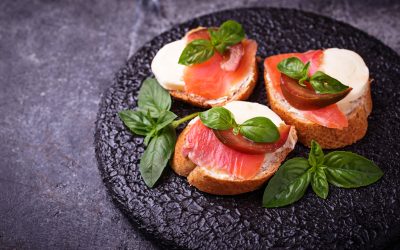 Crostini with salmon, mozarella, tomato and basil. Italian starter or appetizer